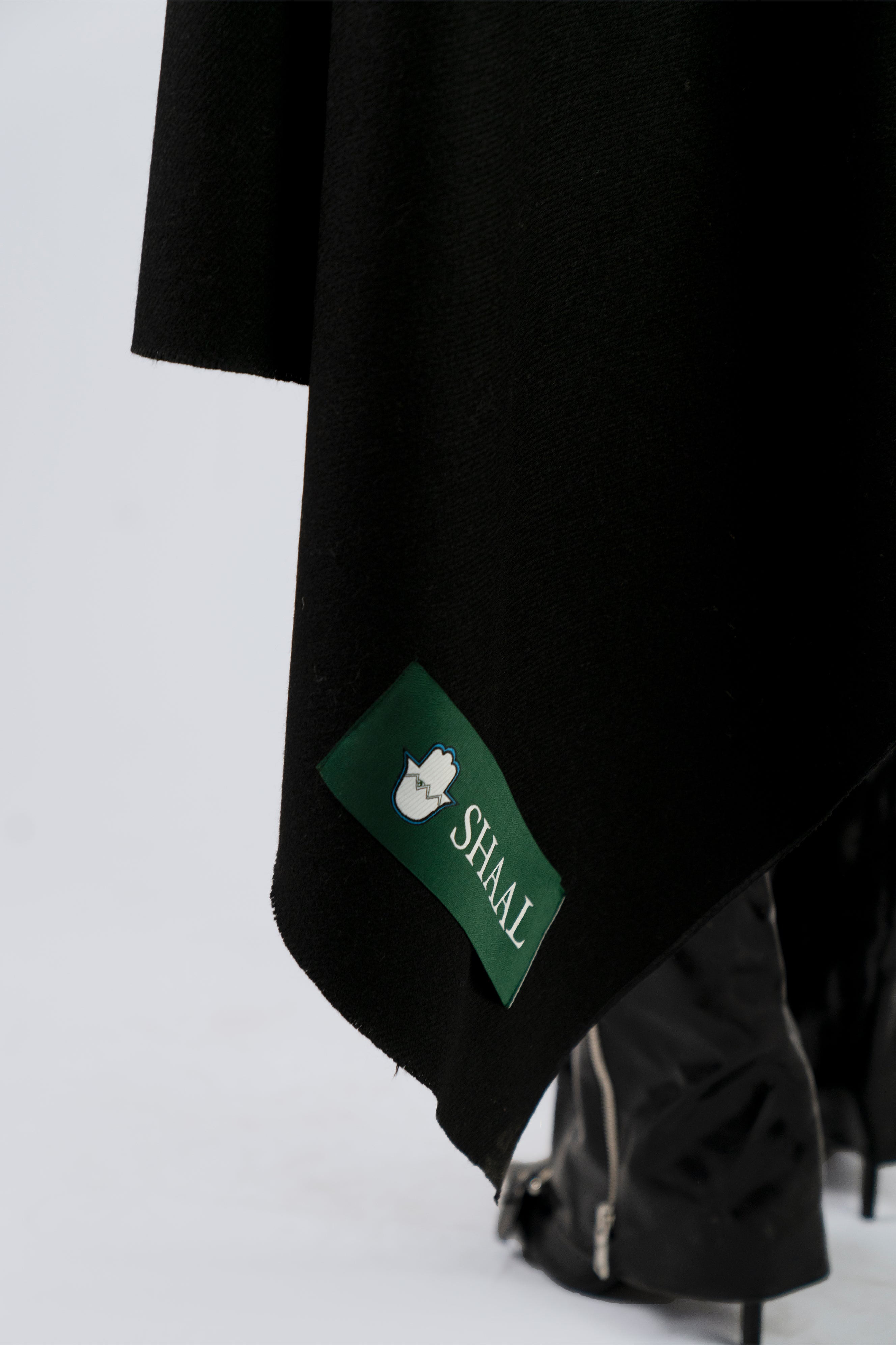 Black heavyweight lamb wool shawl with SHAAL label detail, female model lower body view