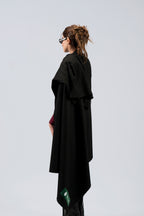 Black heavyweight lamb wool shawl wrapped around female model with sunglasses, three-quarter back view