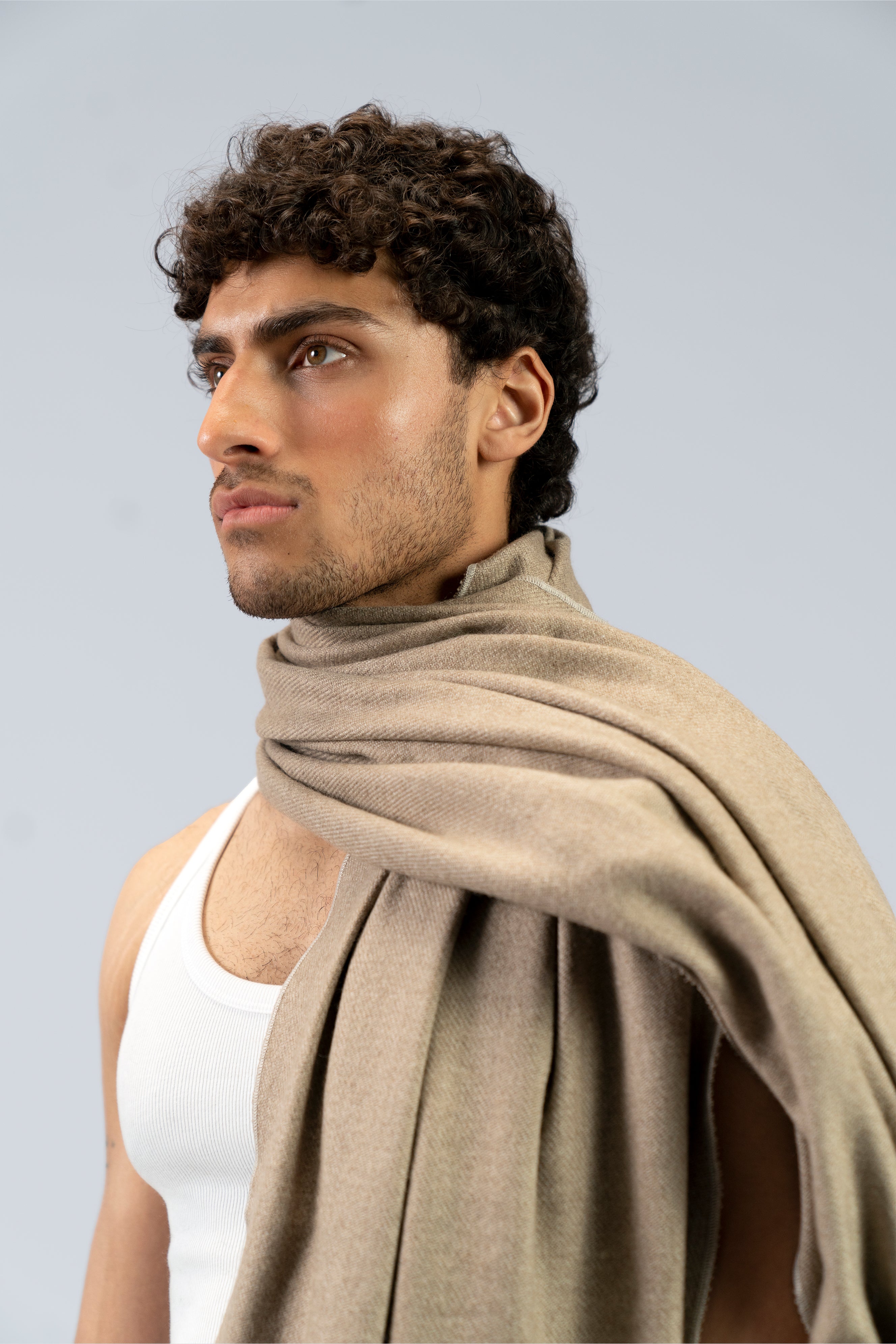 Beige heavyweight lamb wool shawl close-up draped over shoulder of male model, three-quarter view