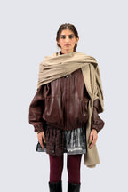 Beige heavyweight lamb wool shawl over leather jacket on female model, front view