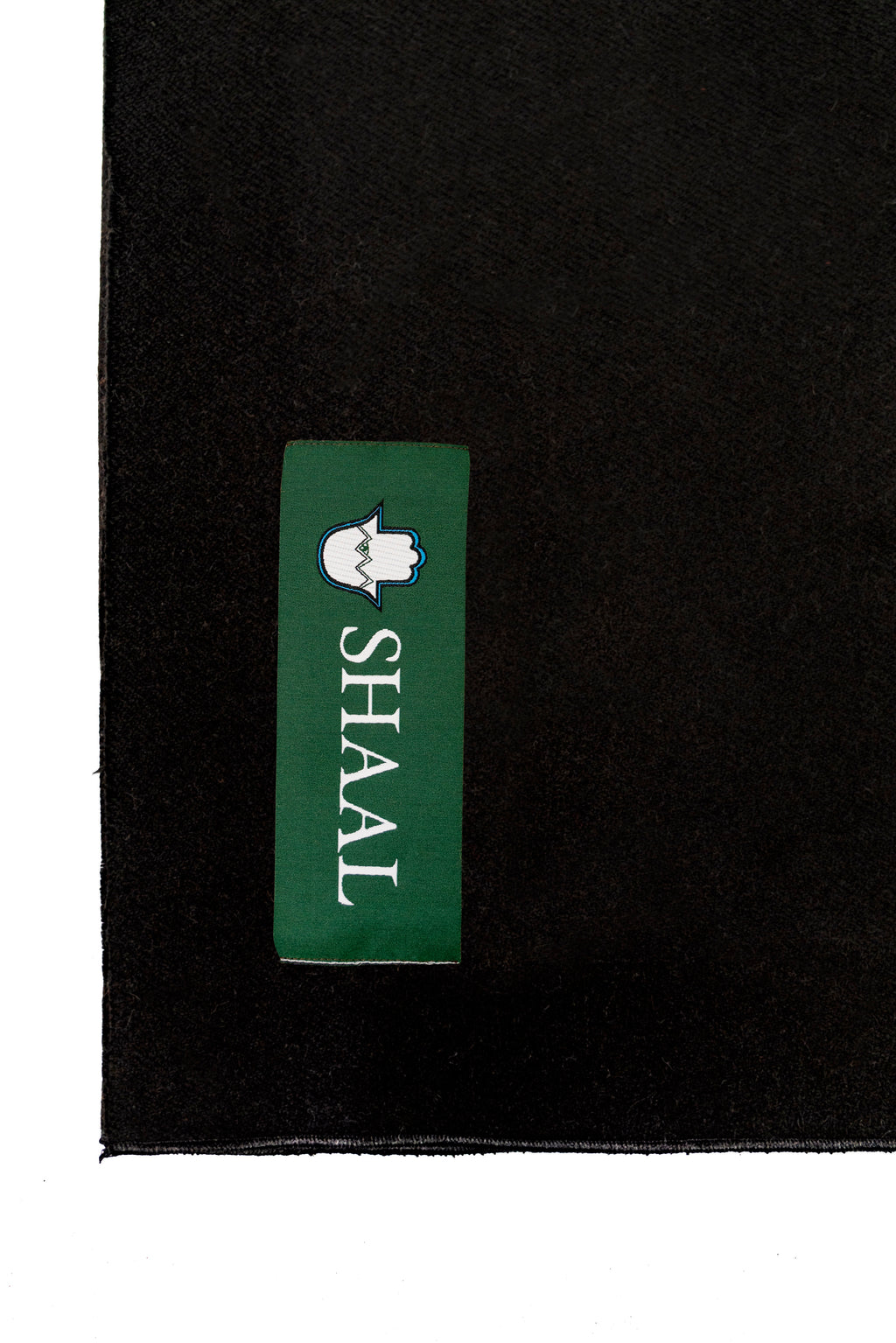 Black heavyweight lamb wool shawl detail of green SHAAL woven label on white background